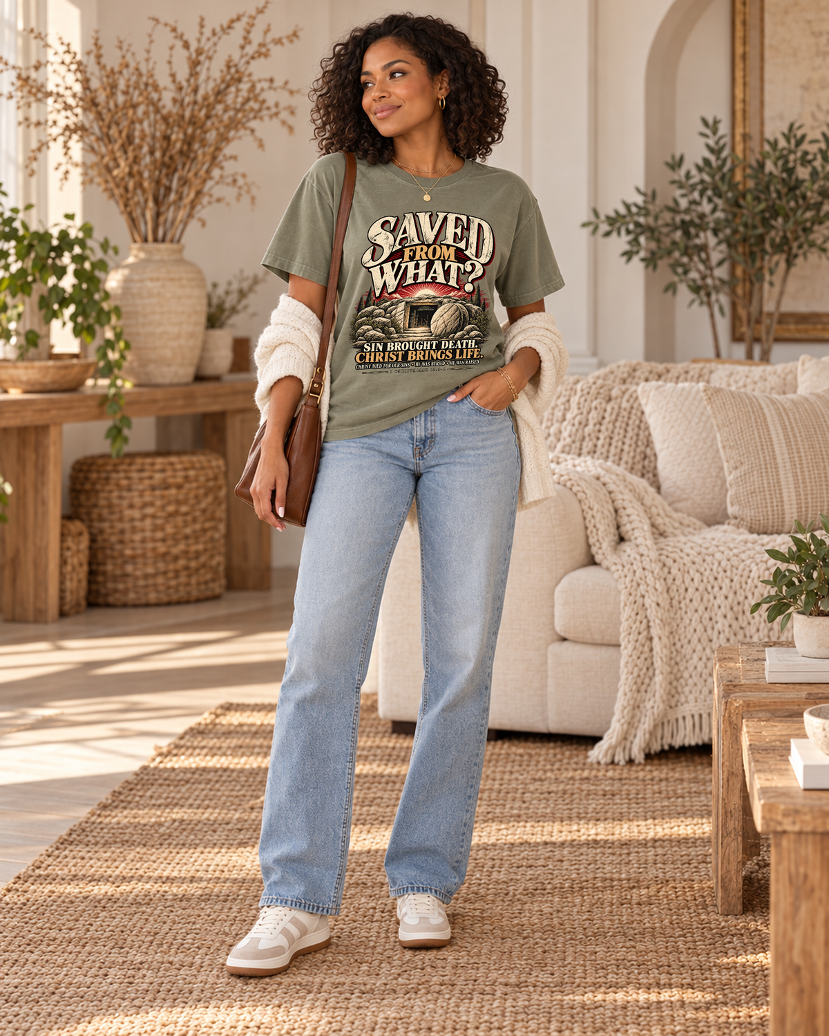 Womens collection lifestyle: Saved From What original artwork on sage tee with ivory knit cardigan, gold jewelry and cognac bag in Royal Stitch boutique interior