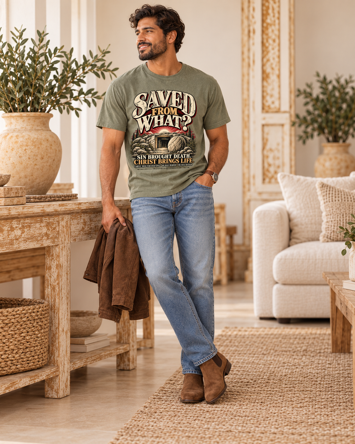 Mens collection lifestyle: Saved From What original artwork on sage tee, styled with denim and suede boots in Royal Stitch warm ivory boutique interior